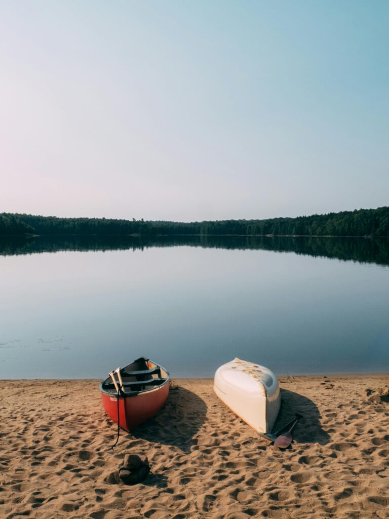 Tranquil scene of boats on a sandy beach by a calm lake in Kawartha Lakes, Ontario.